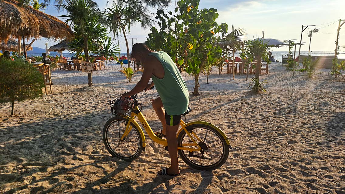 Hombre subido a una bicicleta en la playa de Gili Air