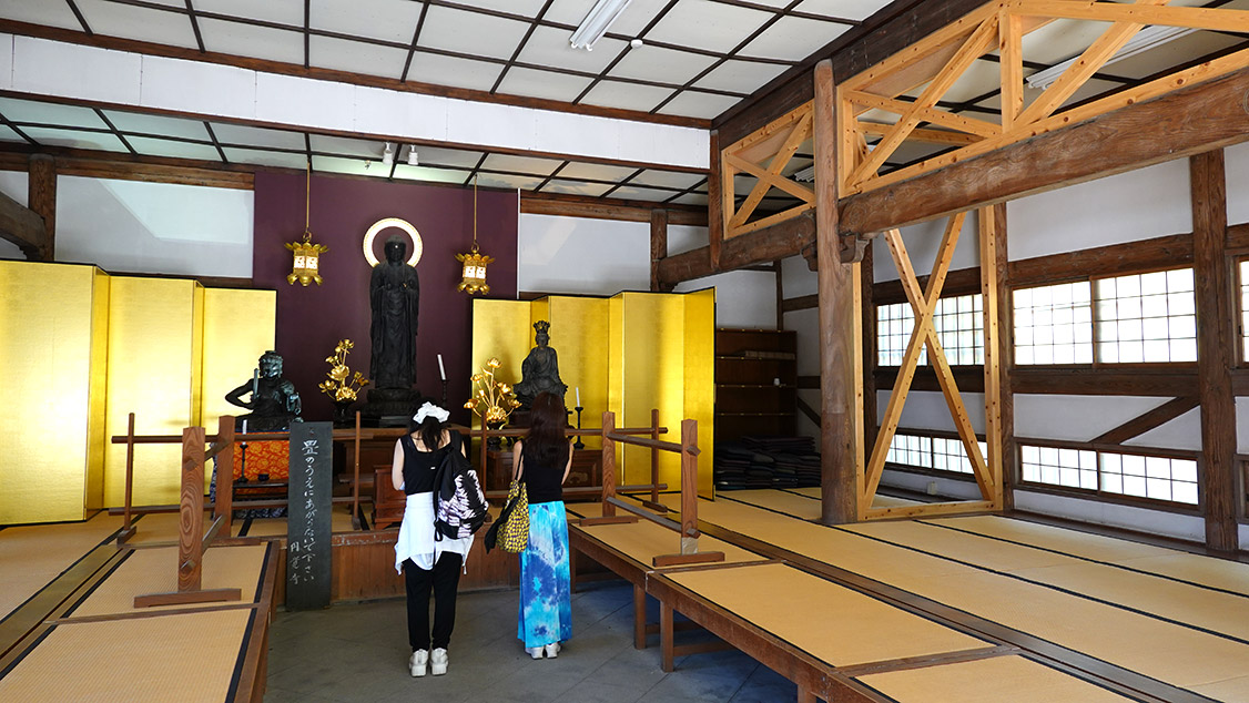 Interior de un templo con suelo de tatami y estatua